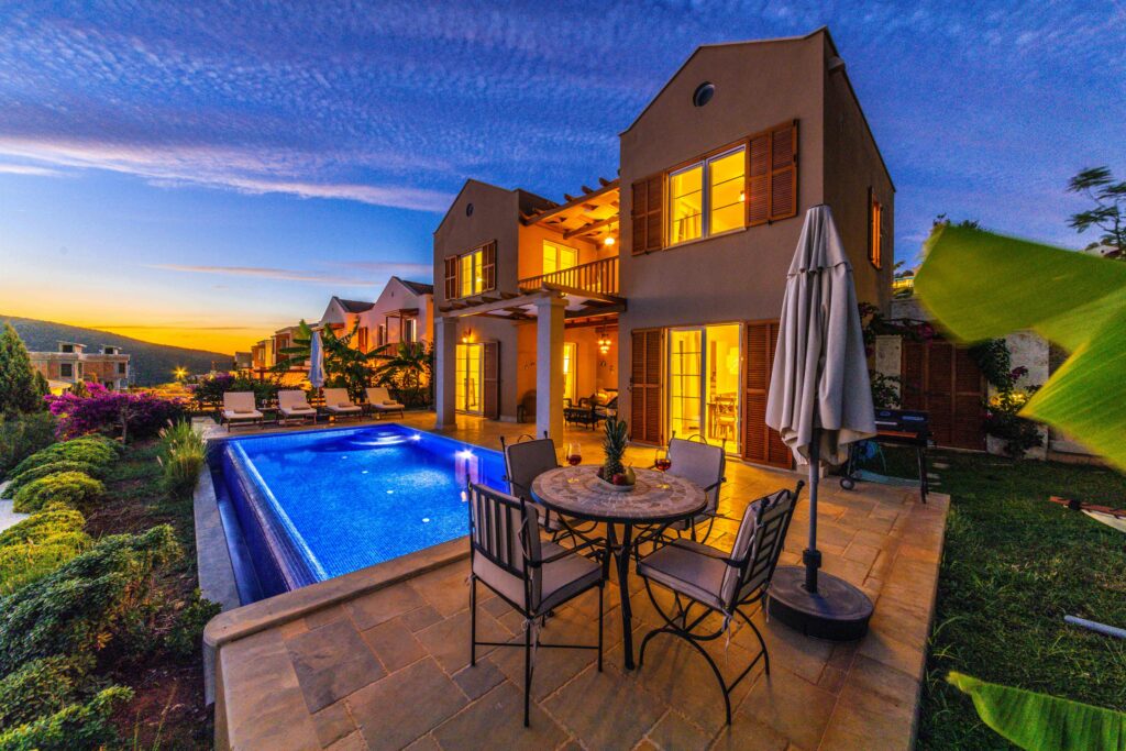 Charming holiday villa with illuminated pool at sunset, ideal for relaxation and luxury retreats.