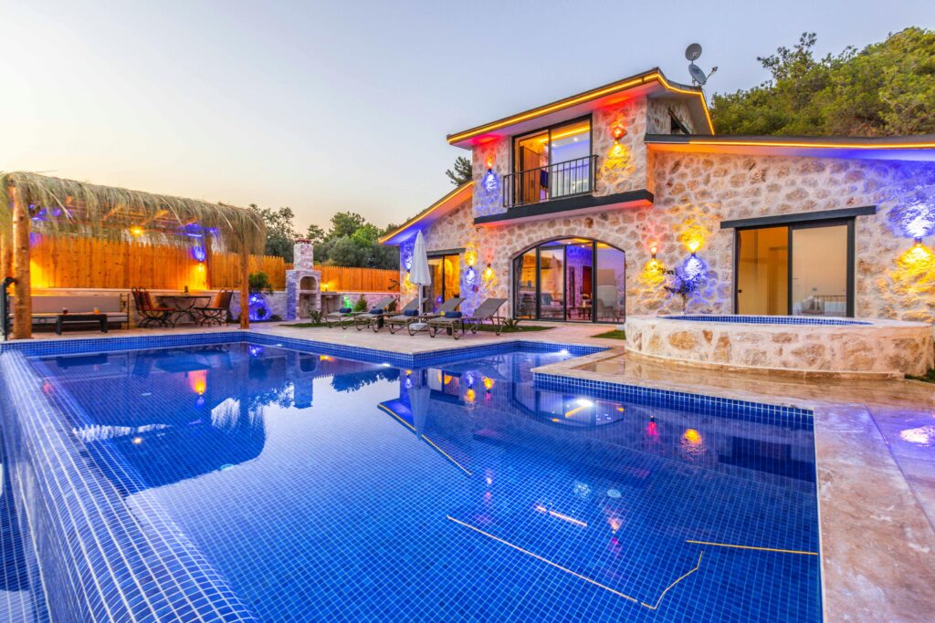 Elegant stone villa with illuminated facade, pool, and relaxing outdoor area.